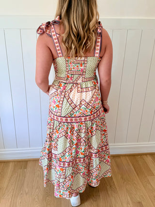 Woman wearing a patterned dress with a white paneled wall background