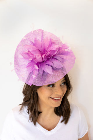 Woman wearing a pink fascinator hat against a white background