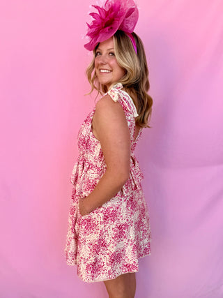 Woman wearing a floral dress and pink headpiece against a pink background