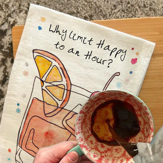 Napkin with drawing of a glass of juice and a slice of lemon, held by a person with a cup of coffee, on a wooden surface.