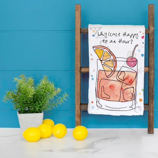 Tea towel with cocktail illustration and text on a wooden rack against a blue wall with lemons and a plant.