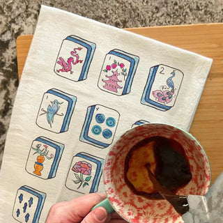 Towel with tarot card designs on a wooden surface with a cup of coffee.