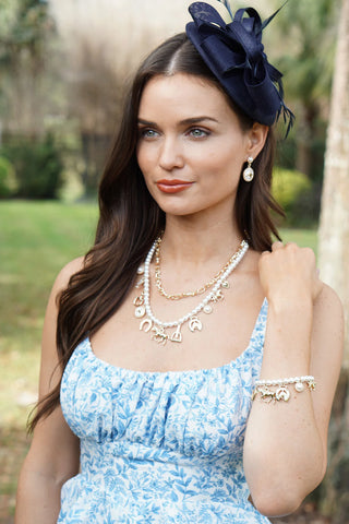 Woman wearing a blue floral dress with a navy fascinator in an outdoor setting