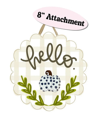 A decorative hanging sign with a scalloped cream border, a gingham background, the word "hello" in dark script, a small polka-dotted pumpkin, green leafy branches, and an "8" Attachment" label above.