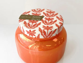 Orange jar with a floral-patterned lid on a white background