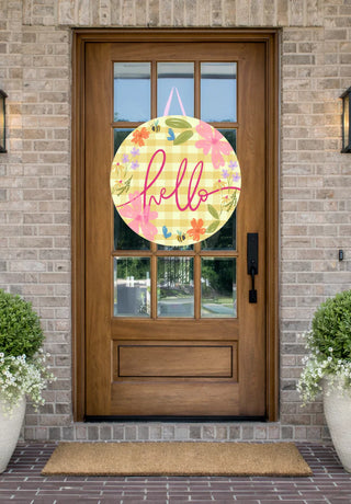 Decorative 'hello' sign with flowers on a wooden door of a house.