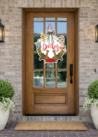 Decorative door hanger with 'Dorby' on a wooden front door of a house.