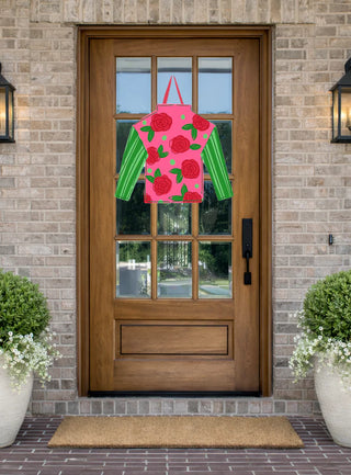 Wooden front door with a pink and green floral design on a brick wall background
