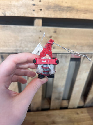 Small gnome ornament with 'Sofia' tag held by a hand against a wooden background