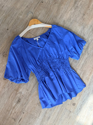 Blue blouse on a wooden hanger against a wooden floor background