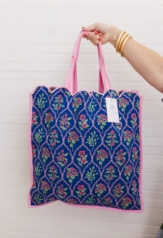 Tote bag with floral pattern held by a hand against a white background