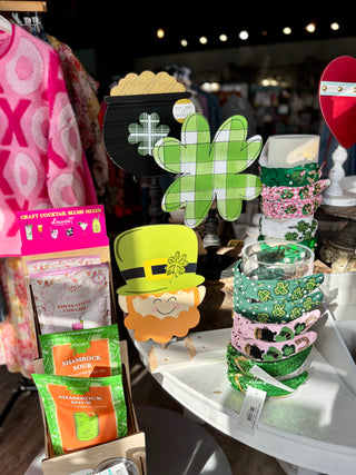 St. Patrick's Day-themed decorative items including a leprechaun hat and clover-shaped signs on a store shelf.