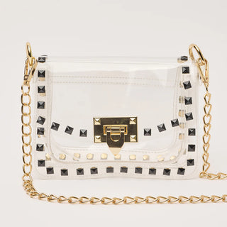 Clear handbag with gold chain strap and black studs on a white background