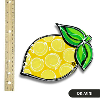 Decorative lemon-shaped object with a green leaf next to a ruler for scale on a white background.
