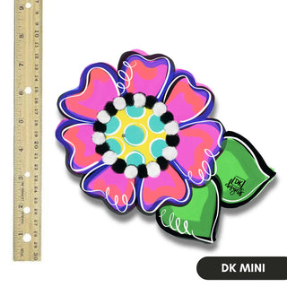 Colorful flower-shaped object with beads next to a ruler on a white background