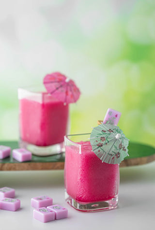 Two glasses of pink drinks with umbrellas on a light background