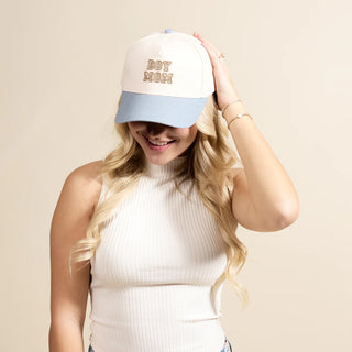 Woman wearing a cap with 'Boy Mom' text on a beige background