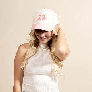 Woman wearing a white cap with 'Girl Mom' text on a beige background