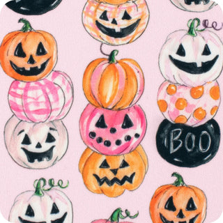A repeating Halloween pattern featuring stacked jack-o'-lantern pumpkins in orange, pink, white, and black, with the word BOO on a black oval, all on a light pink background.