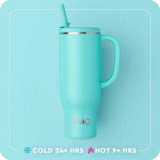 A mint green Swig vacuum-insulated travel tumbler with a matching handle and straw lid, shown against a matching light blue background with product feature text at the bottom.