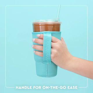 Hand holding a cup with a turquoise sleeve against a light blue background