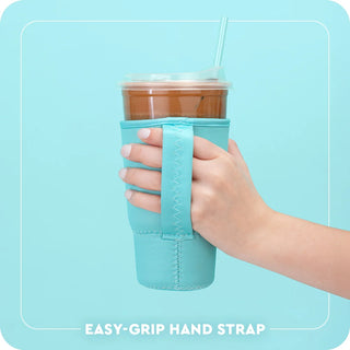 A hand holding a clear plastic cup with a straw and brown drink, wrapped in a light blue neoprene-style hand strap sleeve. The text at the bottom reads 'EASY-GRIP HAND STRAP' on a light blue background with a thin white border.