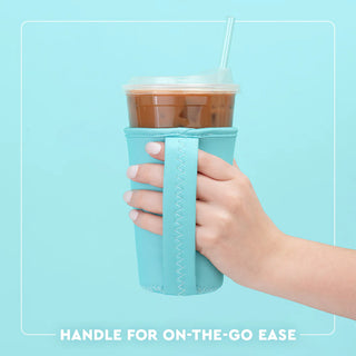 Hand holding a cup with a turquoise sleeve against a light blue background
