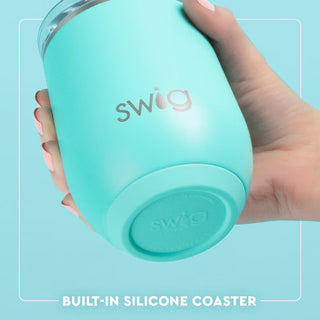 Hand holding a turquoise Swig tumbler with a light blue background