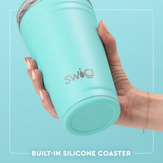 Hand holding a turquoise Swig tumbler with a light blue background