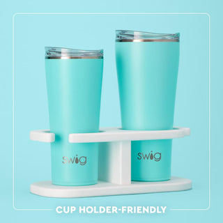 Two turquoise tumblers with a white stand on a light blue background, featuring the 'swig' brand.