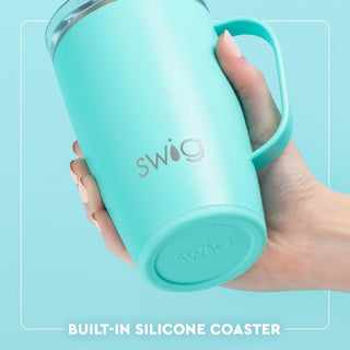 Turquoise Swig tumbler held by a hand with a light blue background