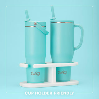 Two turquoise mugs with straws on a white stand against a light blue background