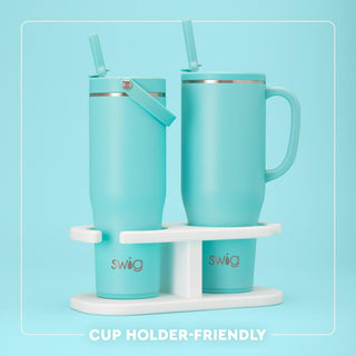 Two turquoise mugs with straws on a white stand against a light blue background
