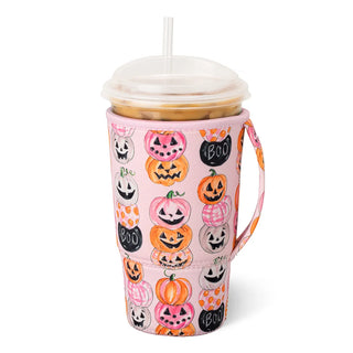 A pink insulated travel tumbler with a clear lid and straw, covered in a Halloween-themed pattern featuring jack-o'-lanterns, ghosts, and the word 'BOO'.