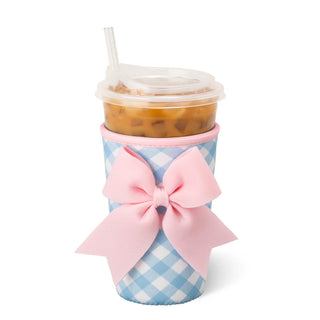 Coffee cup with blue checkered sleeve and pink bow on a white background