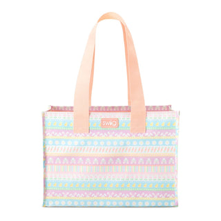 A Swig brand tote bag featuring a pastel multicolor horizontal pattern with pink, blue, yellow, and white stripes, complete with peach-colored shoulder straps and a small pink Swig logo patch on the front.