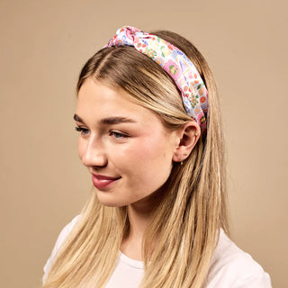 Woman wearing a colorful floral headband against a beige background