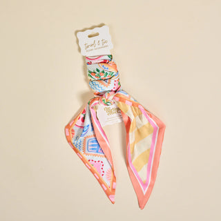 Colorful patterned hair scarf on a beige background with a visible brand label.