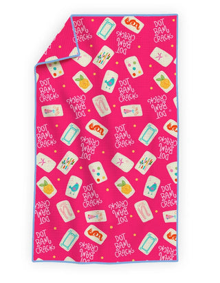 A folded pink towel or blanket with a playful all-over print of white cards, flip-flops, sunglasses, and the phrase 'DOT RAM BAM CRICK' in white text, with a light blue border.