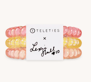 Set of pink and yellow hair ties with a Teleties branded card on a white background