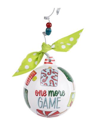 Decorative Christmas ornament with 'one more game' text and a green bow on a white background