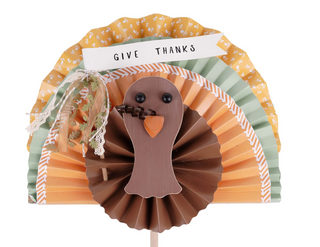 Decorative paper turkey with 'Give Thanks' sign on a white background