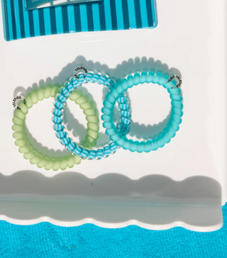Set of green and blue hair ties on a white background with a blue border.