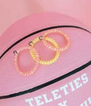 Pink basketball with 'Teleties' branding and colorful bracelets on a pink background