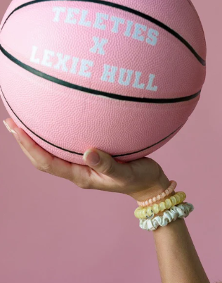Pink basketball with 'Teleties x Lexie Hull' text held by a hand against a pink background