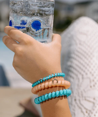 Hand wearing multiple bracelets with a blurred background