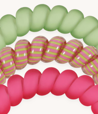 Set of colorful spiral hair ties in pink, green, and red on a white background