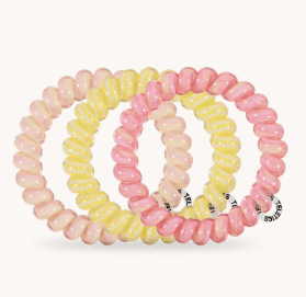 Set of three pink and yellow spiral hair ties on a white background