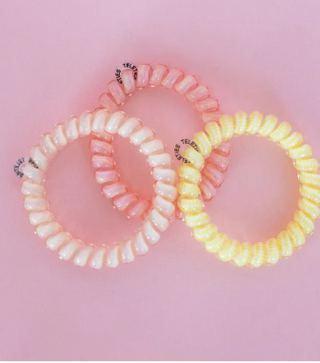 Two hair ties, one pink and one yellow, on a pink background