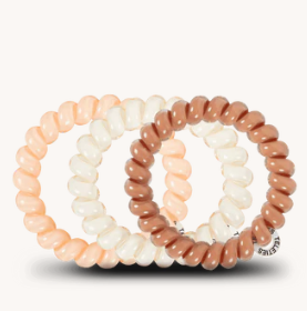 Set of three hair ties in peach, white, and brown on a white background